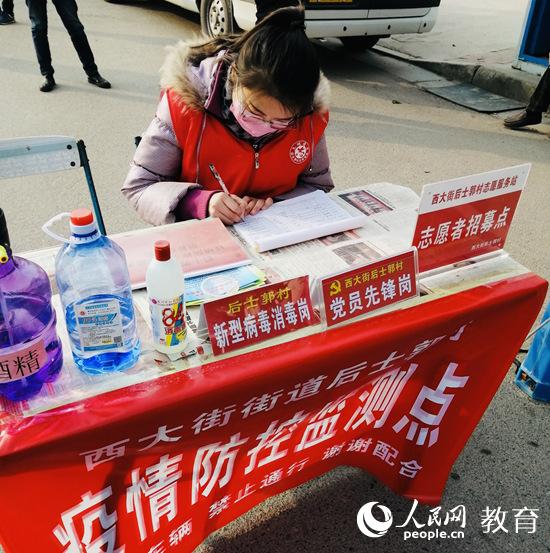 中国石油大学(华东)2019级英语专业学生徐艺甜在家乡参加志愿服务,为来往车辆做登记(学校供图)